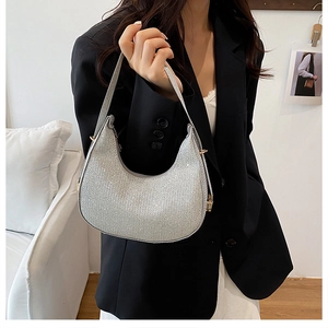 Detail of silver glitter crescent bag with shiny texture and golden metal zipper