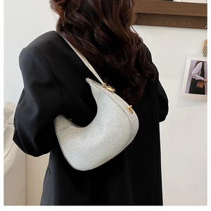 Detail of silver glitter crescent bag with gold metal hardware worn by a model