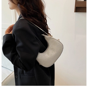 Close-up of sparkling silver sequin crescent hobo bag worn with a black blazer