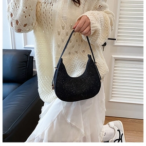 Detail of black crescent hobo bag with sparkly sequins worn over a shoulder