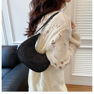 Sparkly black crescent shoulder bag shown on model with white knit sweater outfit
