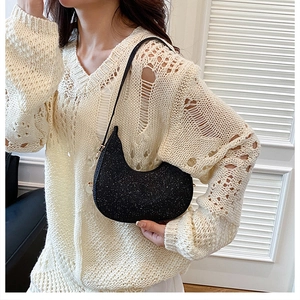 Détail du sac hobo à paillettes noires avec fermeture dorée porté par un mannequin
