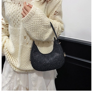 Close-up of black sequined crescent hobo bag with gold buckle on a model wearing knitwear