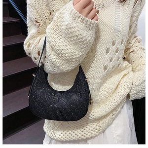 Close-up of black crescent shoulder bag with shimmering rhinestones and gold buckles