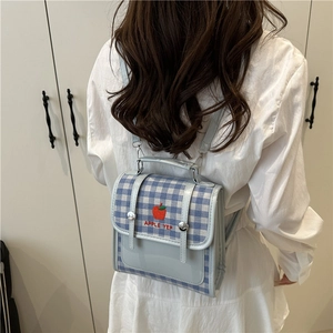 Blue and white plaid mini backpack with red apple embroidery worn by a model