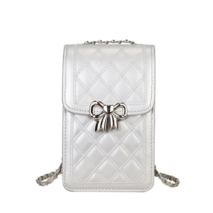 Silver quilted mini phone bag with metal bow and chain strap in sleek minimalist design