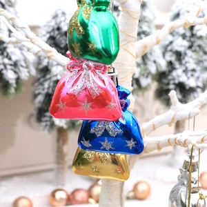 Christmas gift bag ornaments with snowflakes and glitter bows hanging on snowy tree branches