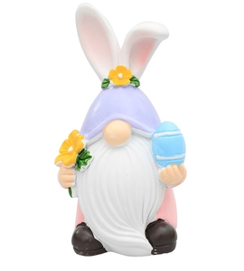 Dettaglio gnomo pasquale in resina con orecchie da coniglio che tiene un fiore e un uovo