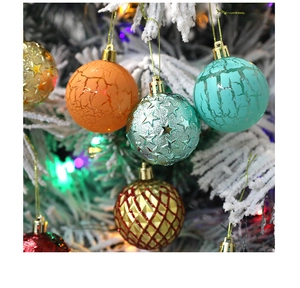 Detail view of multi-textured Christmas baubles hanging on a snowy tree with festive lights