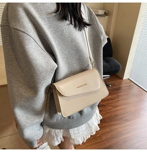 Detail view of the beige patchwork crossbody bag with textured fabric and leather strap