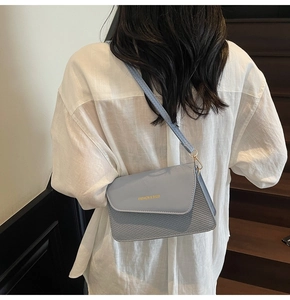 Detail of light blue crossbody bag with woven texture and gold fashion lettering