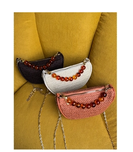 Detail of woven crescent bags with amber resin bead handles and gold metal chains