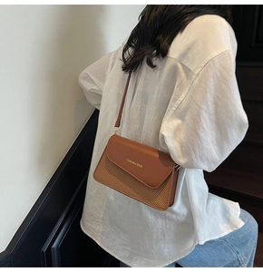 Brown leather and straw patchwork shoulder bag worn over a white linen shirt and jeans