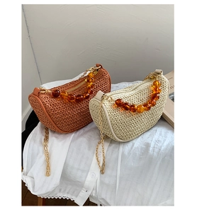 Detail of woven crossbody bags featuring amber bead handles and golden metal chains