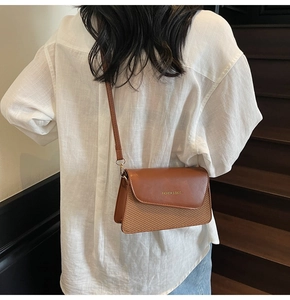Detail showing brown leather crossbody bag with woven texture and gold metal hardware