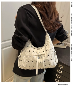 Side view of a white ruched underarm bag with rabbit prints and heart pendant on a model