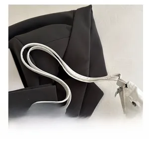 Close-up of quilted white tote bag with black embroidered bows and silver zipper detail
