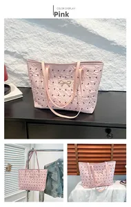 Detail of pink floral tote bag with embossed pattern and gold bow charm accent