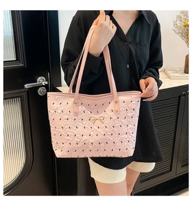 Pink quilted tote bag with rabbit print and golden bow detail held by a model