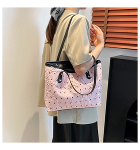 Detail of pink quilted tote bag with black monogram print and gold bow hardware detail