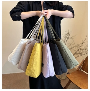 Multiple colors of lightweight nylon tote bags shown in cream, gray, yellow, and green