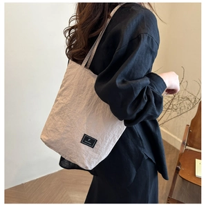Detail of minimalist beige tote bag showing fabric texture and woven brand label