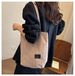 Detail of minimalist beige canvas shoulder bag with branded label in aesthetic home setting