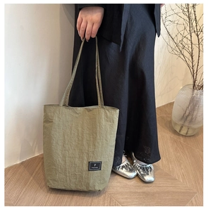 Olive green nylon tote bag featuring a brand label and natural wrinkled fabric texture