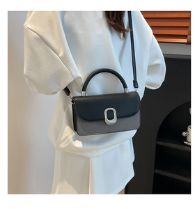 Detail of crossbody bag with silver oval buckle and mixed leather texture in black and grey