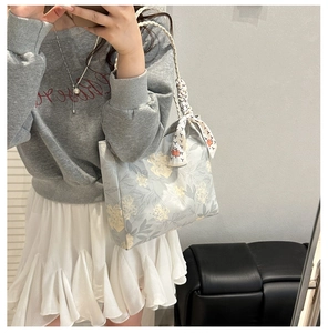 Détail du sac seau en toile à fleurs bleu clair avec anse en corde et foulard décoratif