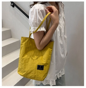 Close-up of ginger yellow tote bag featuring a textured fabric and minimalist logo detail
