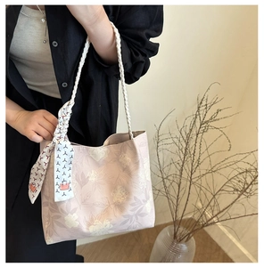 Détail d'un sac cabas en toile brodée de fleurs avec anse en corde et foulard en soie