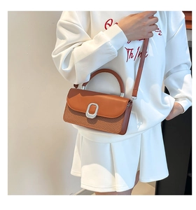 Brown orange crossbody bag featuring woven texture detail and silver oval buckle
