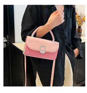 Detail of pink and red textured crossbody bag with silver buckle held by a model