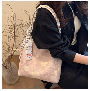 Detailed close-up of pink floral bucket bag with woven strap and silk scarf accent