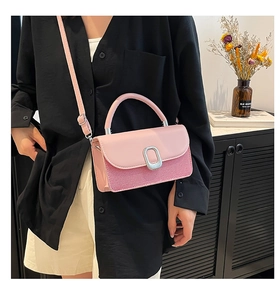 Detailed view of pink crossbody handbag featuring texture contrast and metal clasp buckle