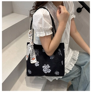 Détail du sac cabas floral noir en toile avec anses en corde et foulard décoratif