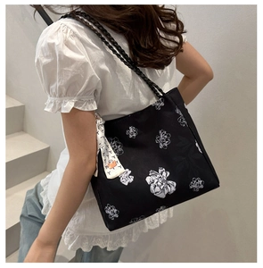 Detail of floral tote bag with braided handles and decorative scarf on a model