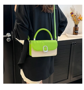 Detail view of contrast stitching and silver oval metal buckle on a green mini crossbody bag