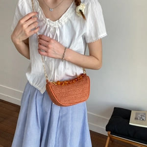 Sac bandoulière orange tressé chic avec perles ambrées et chaîne dorée sur mannequin