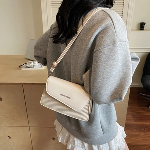 Minimalist square crossbody bag in off-white textured leather shown on model's shoulder