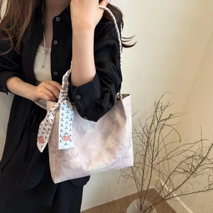 Floral bucket tote bag with woven handles and a decorative silk scarf accessory