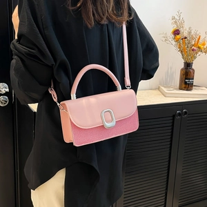 Pink patchwork crossbody bag with silver lock shown on a shoulder in a cozy setting
