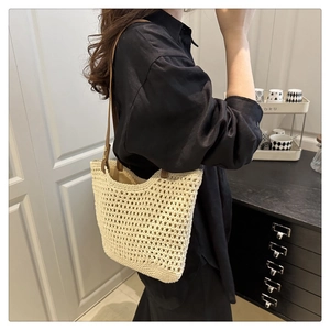 Détail du sac cabas beige tissé avec bandoulières en cuir marron porté à l'épaule