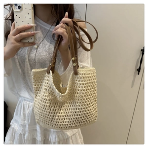 Dettaglio borsa shopper in maglia intrecciata con manici in pelle marrone e rivetti dorati