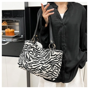 Detailed view of zebra print canvas bag with black leather straps and gold metal rings