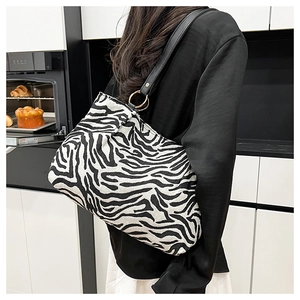 Detail of zebra pattern shoulder bag with black leather strap and golden metal ring