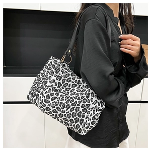 Close-up of leopard print canvas bag with black leather strap and gold ring buckle detail