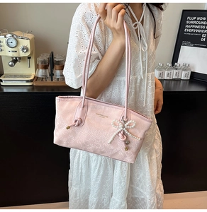 Close-up of pink snake pattern tote bag featuring pearl bow and gold logo detail
