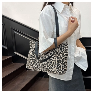 Detail shot of leopard print tote bag with black leather straps and canvas texture